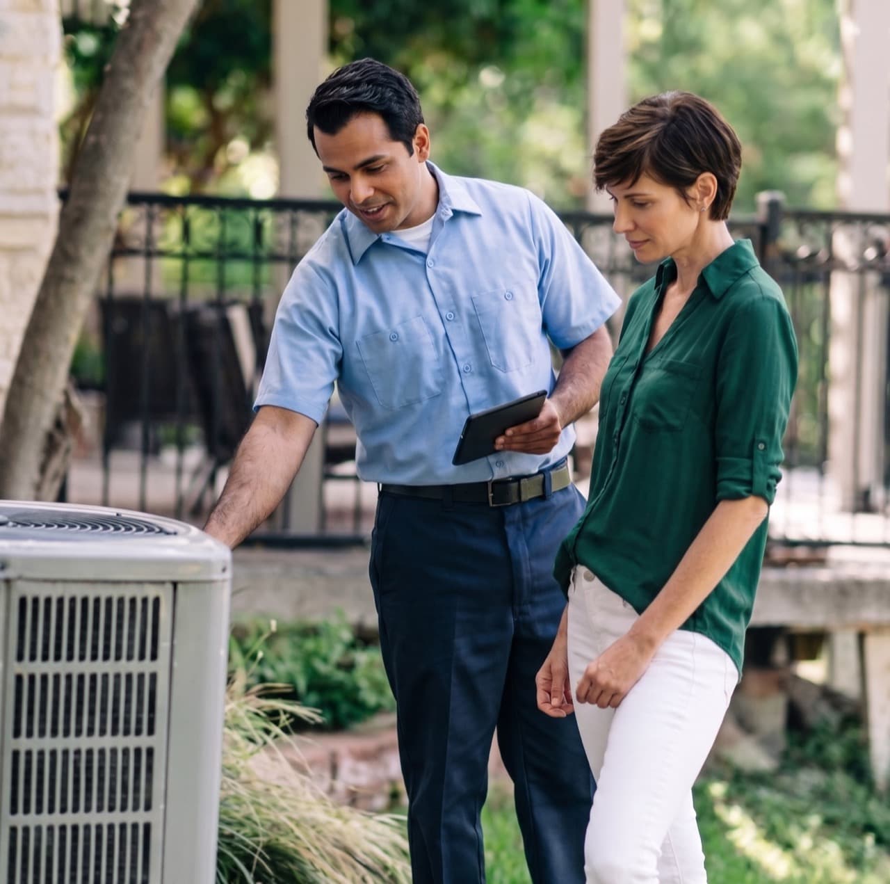 HVAC technician walking a homeowner through her outdoor AC unit.