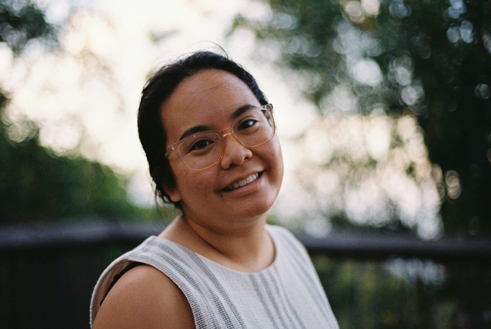 Portrait of a smiling woman in glasses outdoors in soft evening light.
