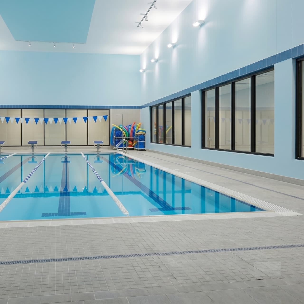 Indoor swim academy pool with lane ropes, pennant flags, and pool noodles